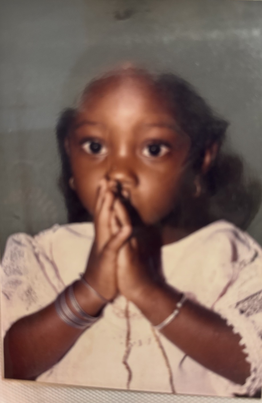 Inès Zongo enfant, les mains jointes devant son visage